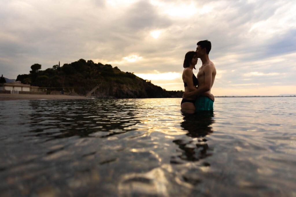 Chloé et Valentin partageant un moment intime dans l'eau au coucher du soleil à la plage de l'Ouille, avant d'arriver à Collioure