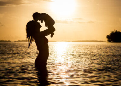 photo de famille d'une mère avec son bébé dans les bras au coucher de soleil