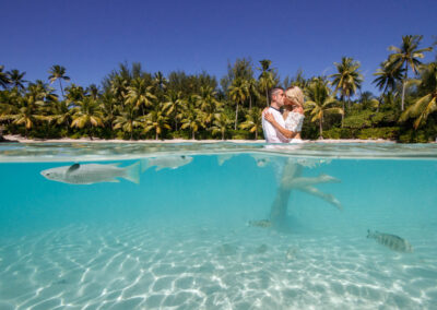 photo d'un couple de mariés dans l'eau avec des poissons